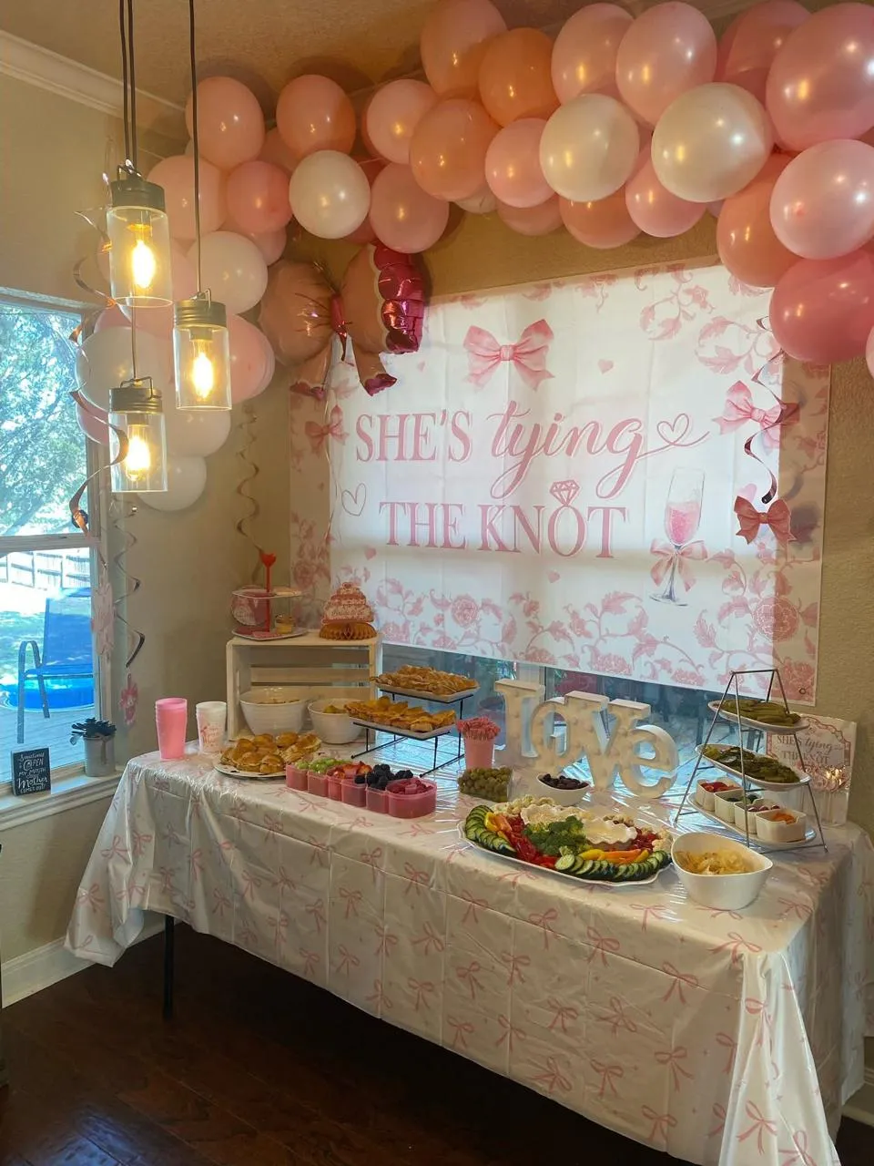 Buffet table in front of a pink bridal shower backdrop