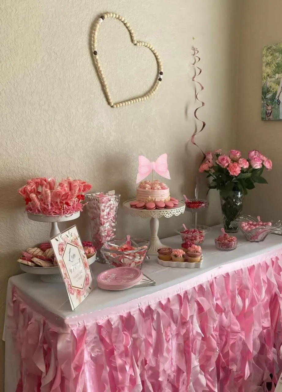 Pink dessert table with ruffled skirting and a beaded heart on the wall